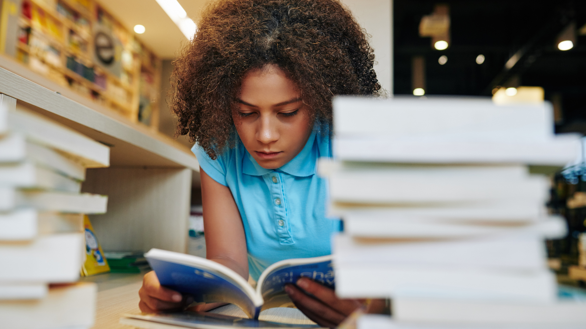 3rd grade student reading a book inside a school library.